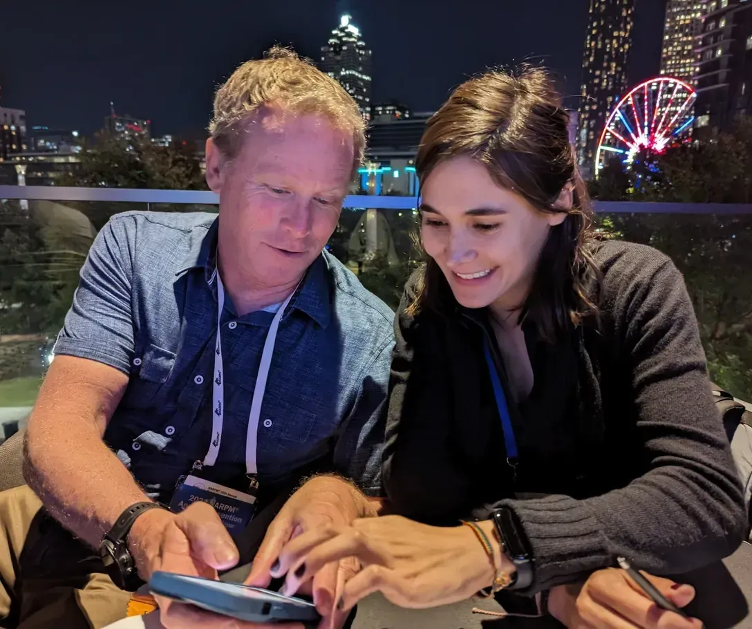 Two conference attendees look at a phone together