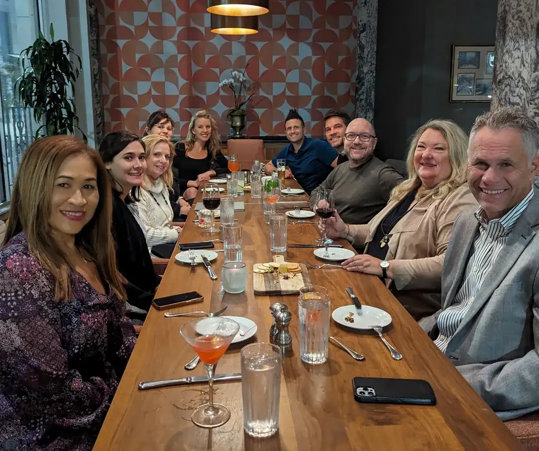 A group of people smiling around a long dinner table